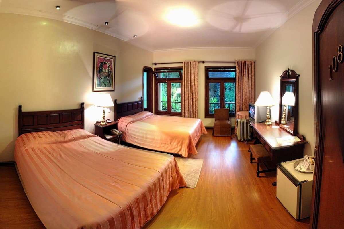 Habitación de hotel con dos camas, un escritorio, una silla, un radiador y una puerta con el número 108.