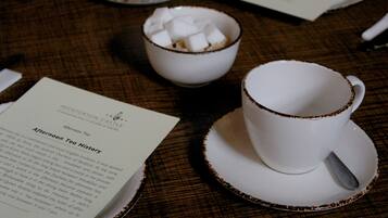 A table with a placemat, a bowl of sugar cubes, a cup with a saucer, and a menu.