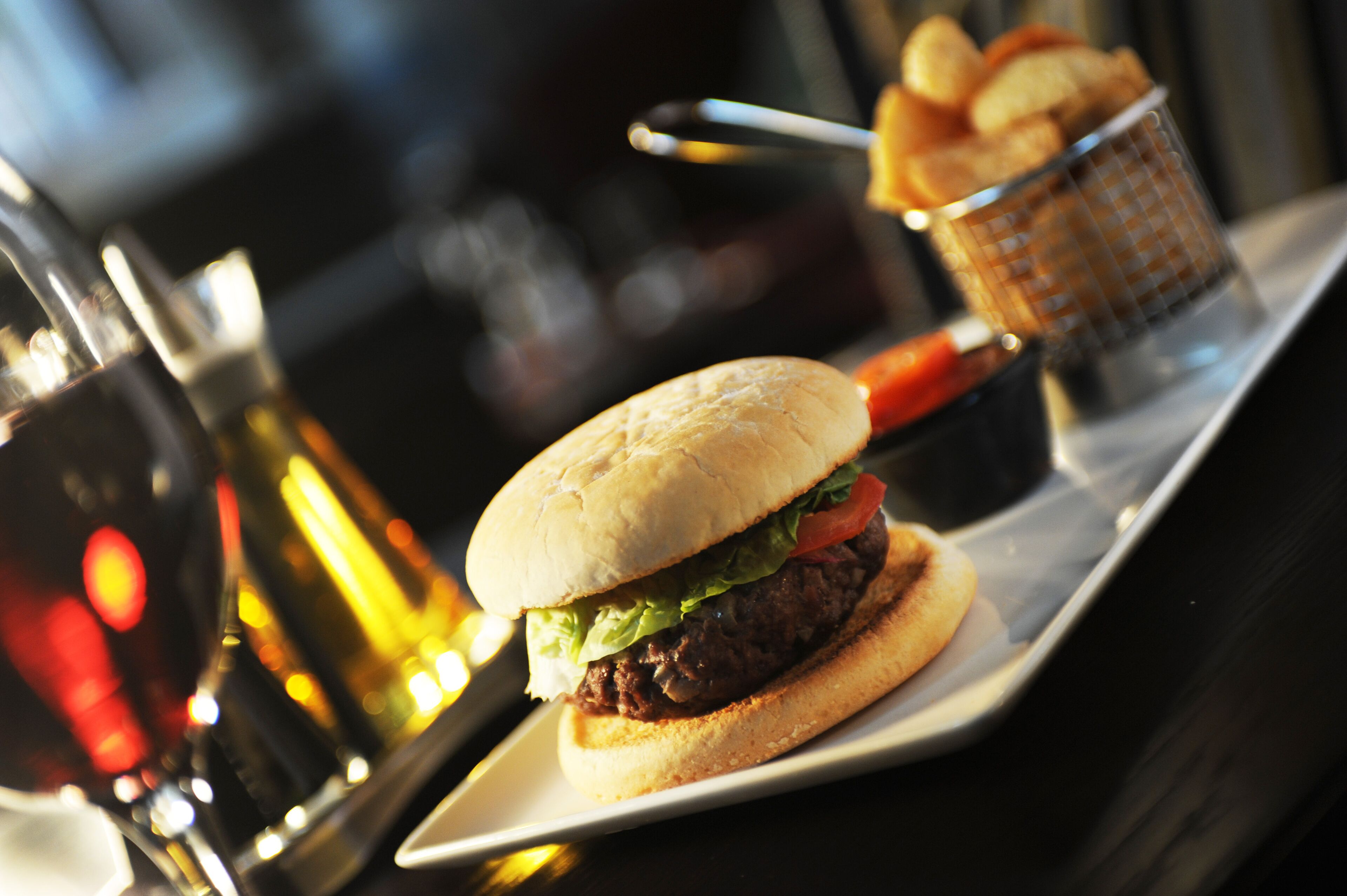 Un piatto con un hamburger, un bicchiere di birra e un cestino di patatine.