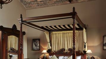 Een hemelbed met houten frame, een spiegel en een nachtkastje met een lamp.