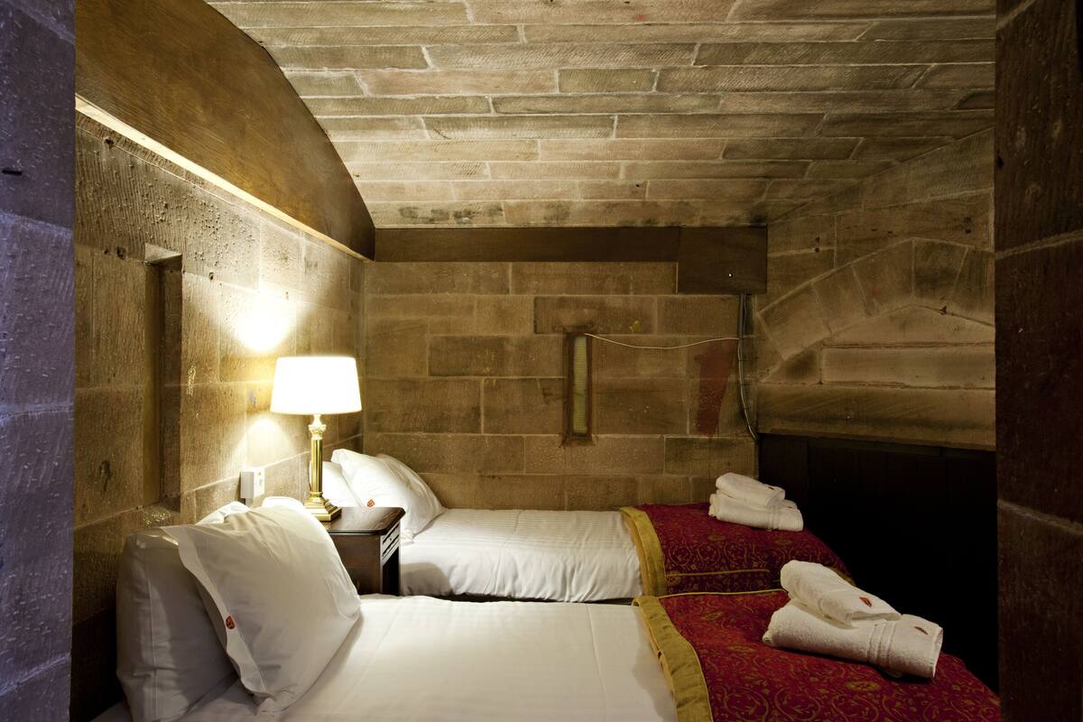 Une chambre avec deux lits, une lampe et une cheminée.