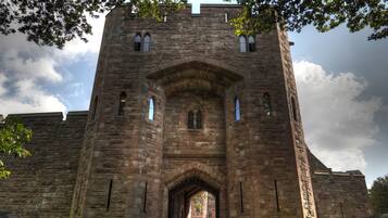 A historic stone building with a central arched entrance and a tower with inscriptions.