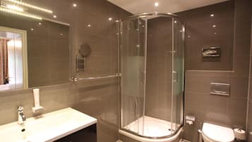Ein modernes Badezimmer mit einer Glasdusche, einem weißen Waschbecken und einer Toilette.
