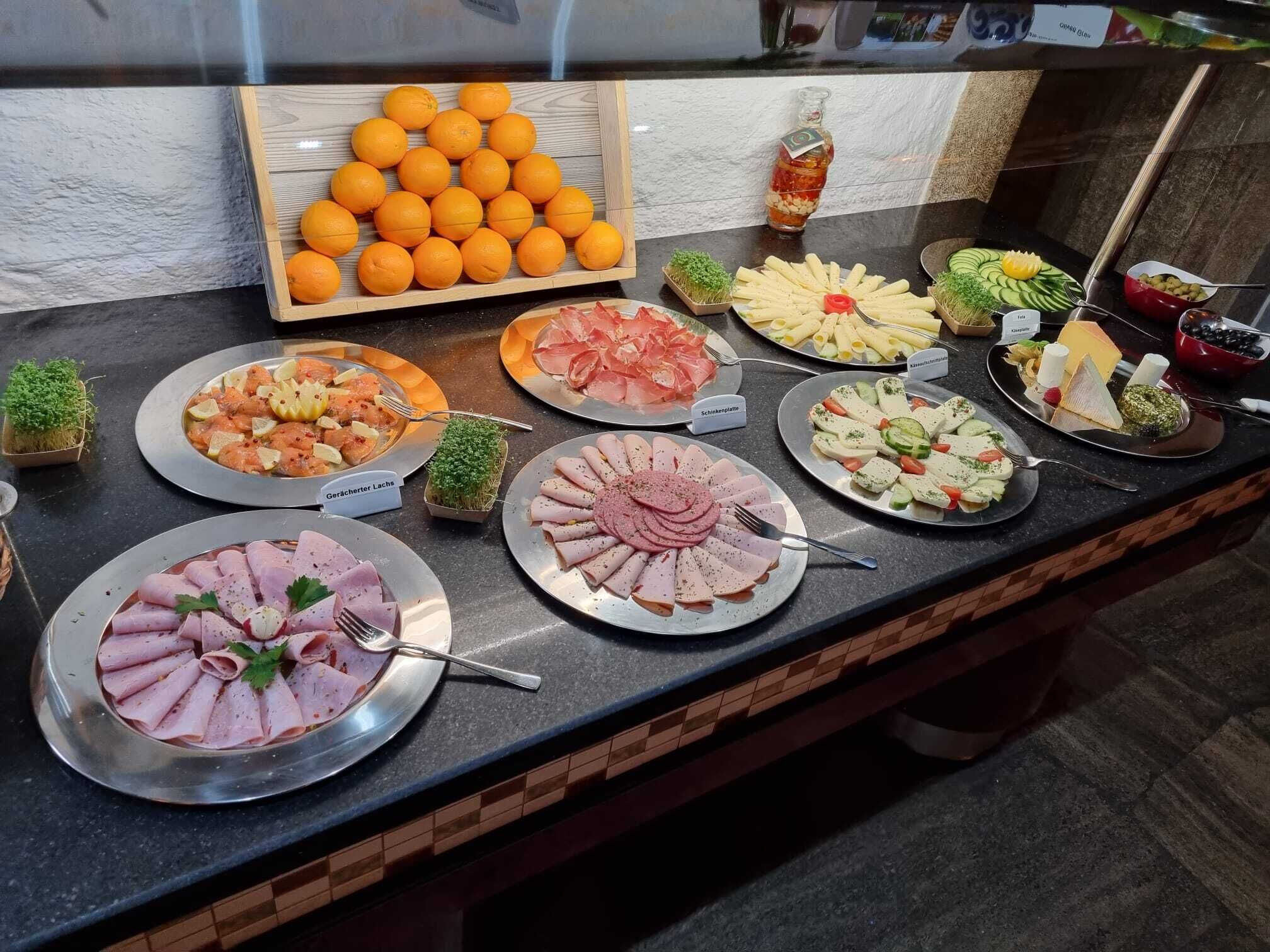 Ein reichhaltiges Buffet mit einer Auswahl an Speisen, darunter Aufschnitt, Käse und Obst.