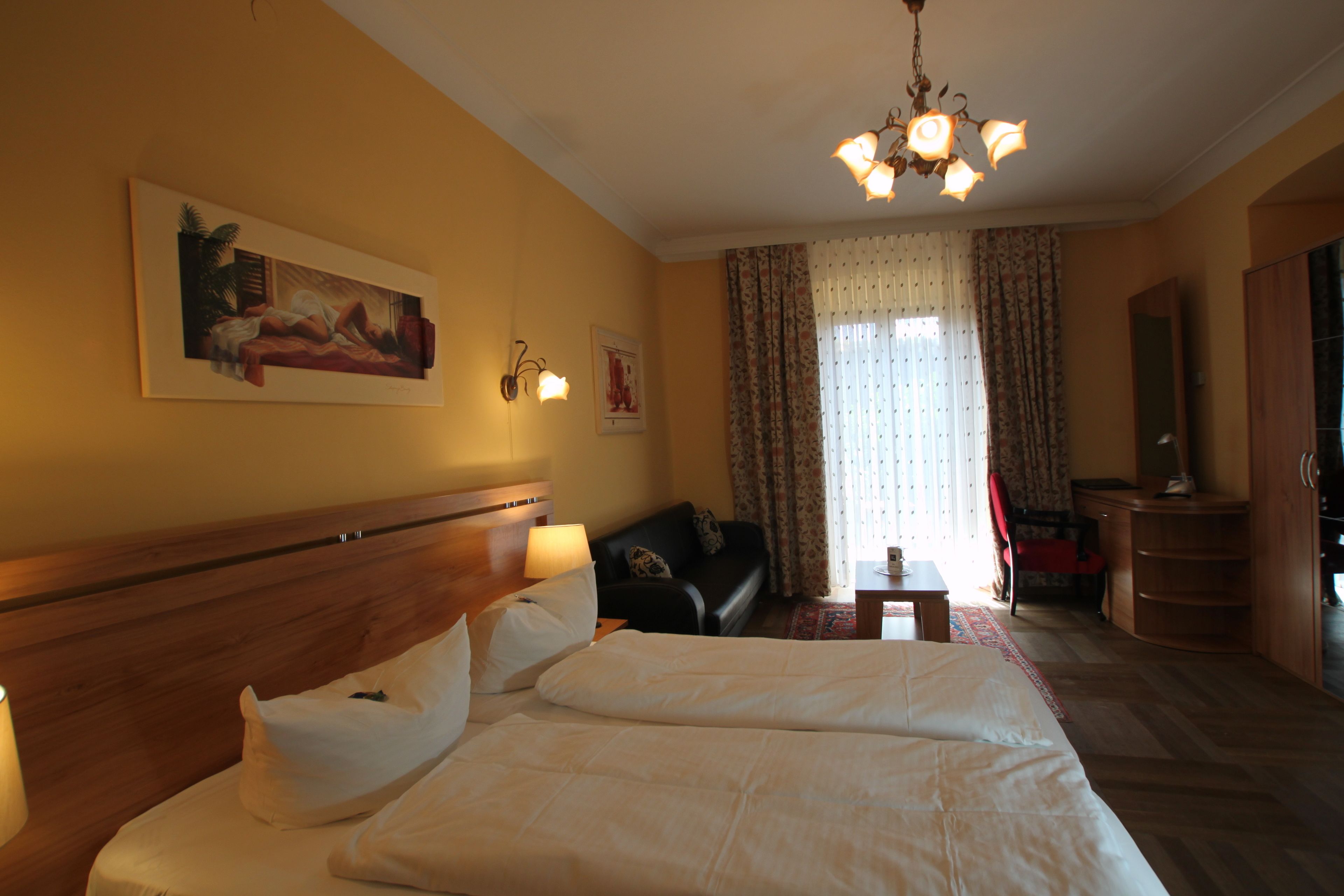 Ein Hotelzimmer mit einem großen Bett, einer Couch, einem Schreibtisch und einem Kronleuchter.