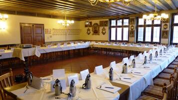 Une salle de conférence avec de longues tables disposées pour une réunion, équipée de plaques nominatives, de bouteilles d’eau et de matériel d’écriture.