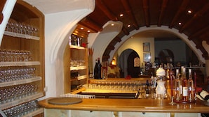 A bar area with shelves of wine glasses and bottles, wooden bar counter, and arched ceiling. - Atlas Grand Hotel (Garmisch-Partenkirchen)