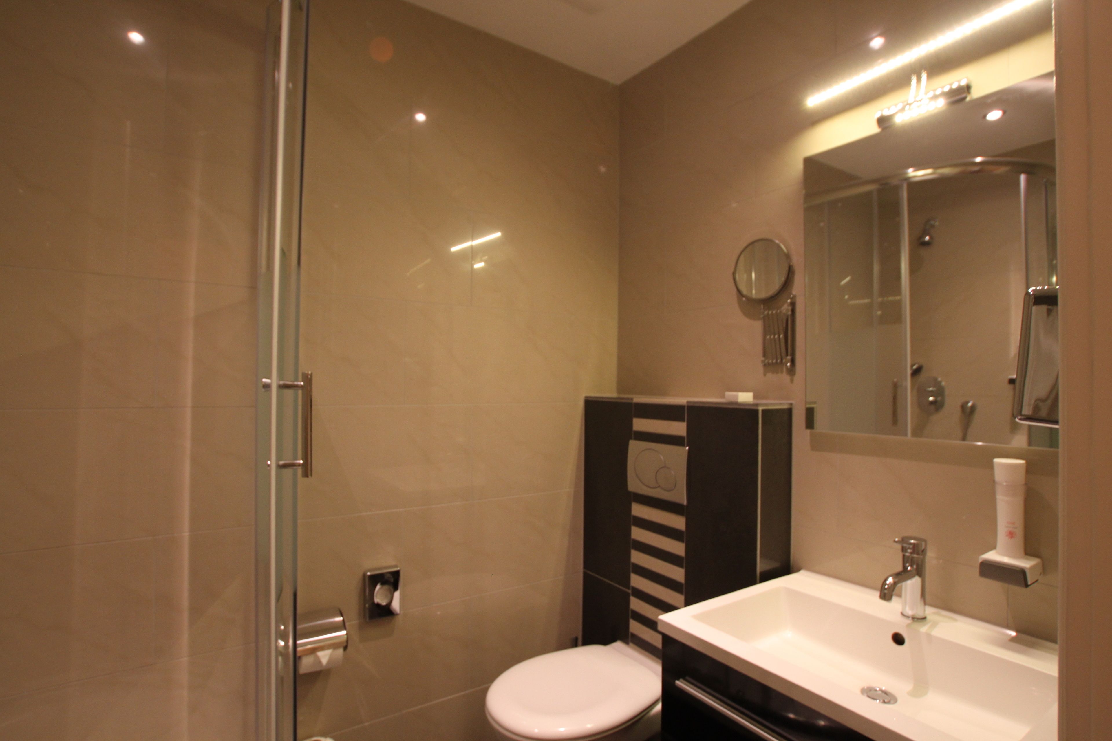 A modern bathroom with a glass shower enclosure, a white sink, and a mirror above the sink.