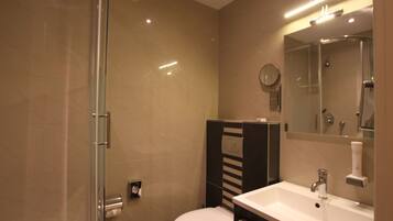 A modern bathroom with a glass shower enclosure, a white sink, and a mirror above the sink.