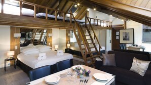 A hotel room with a loft bed, a dining area with a table set for two, and a sofa. - Lion d'Or Paris Hotel (Paris)