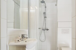 A modern bathroom with a white sink, mirror, and shower.