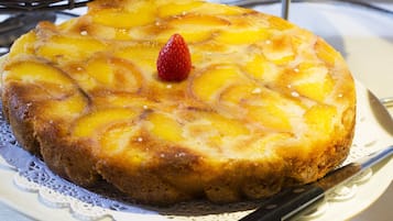 A round fruit-topped cake on a white plate with a knife.