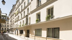 A hotel with multiple floors, large windows, and balconies with plants. - Lion d'Or Paris Hotel (Paris)