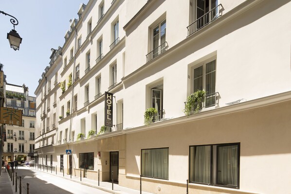A hotel with multiple floors, large windows, and balconies with plants. - Lion d'Or Paris Hotel (Paris)