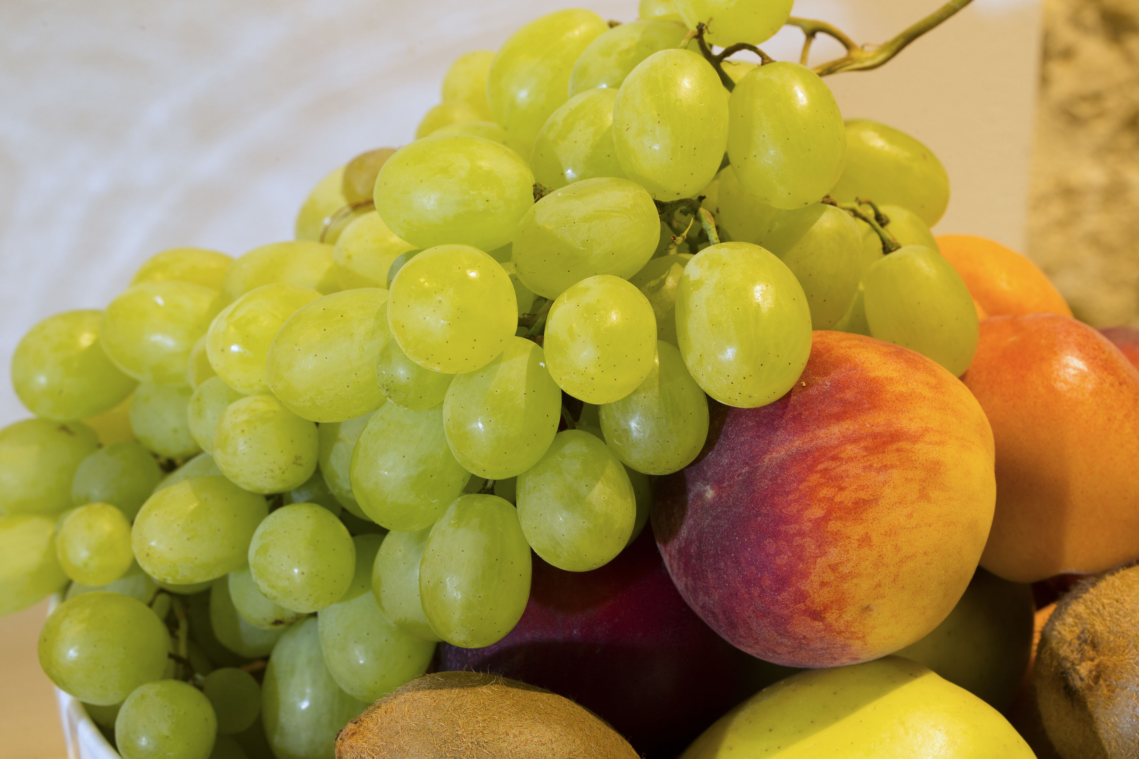 A bowl of fruit including grapes and peaches.