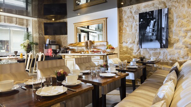 A dining area with a long wooden table set for a meal, a sofa, and a stone wall with a framed picture. - Lion d'Or Paris Hotel (Paris)