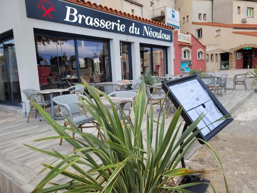 Un área de estar al aire libre con mesas y sillas frente al restaurante Brasserie du Néoulouis.