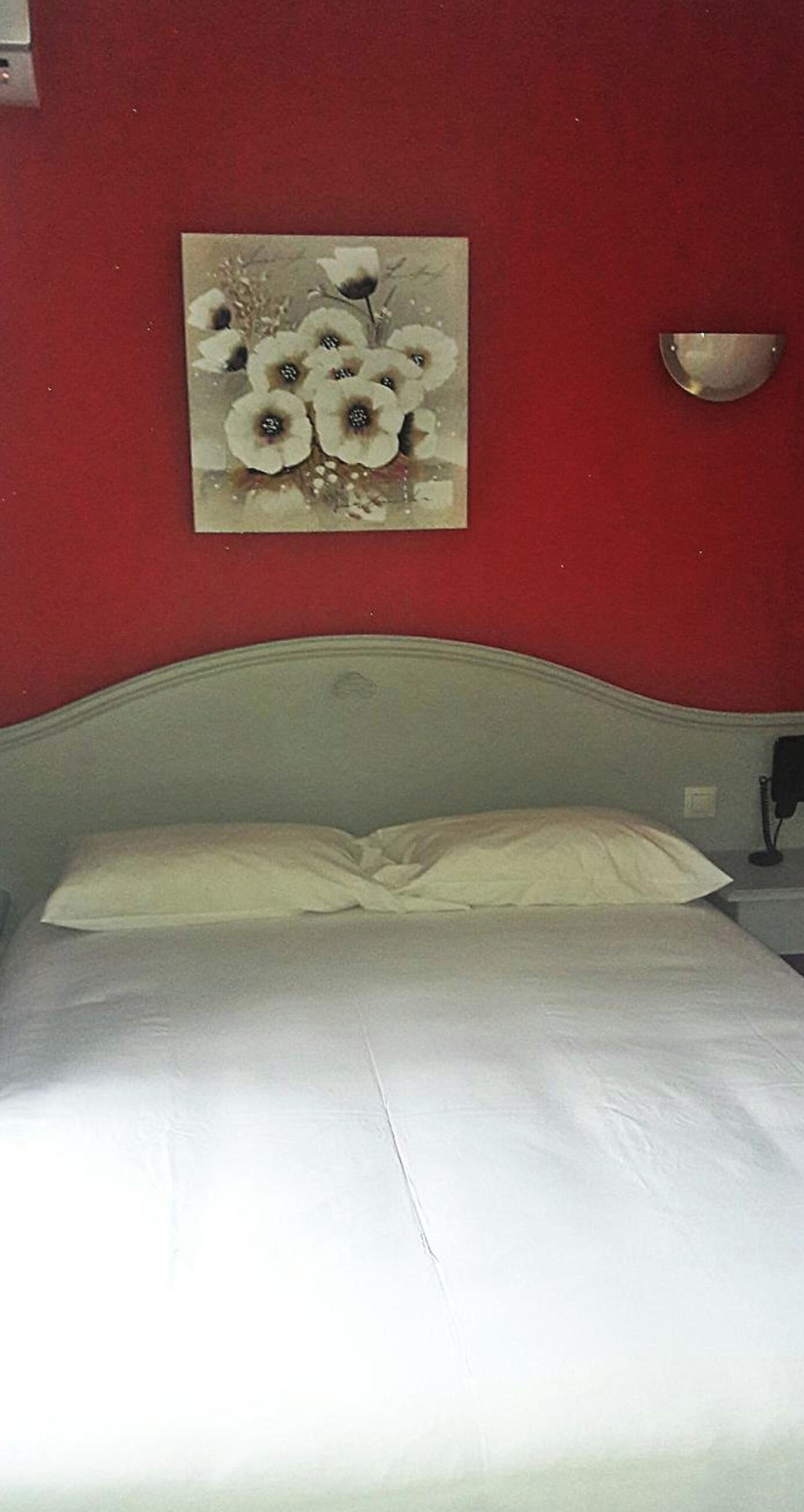 A bed with white bedding in a room with red walls.