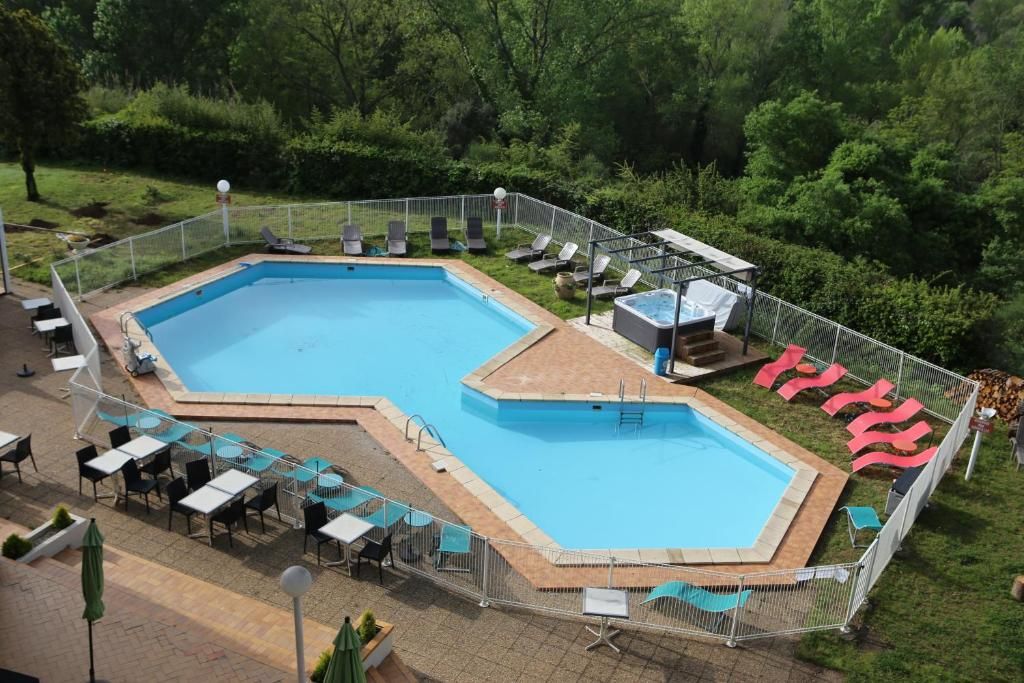 A rectangular swimming pool with a diving platform, surrounded by a fence, and adjacent to a seating area with tables and chairs.