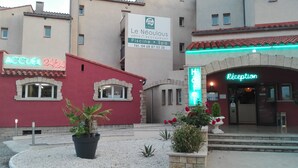 Un hôtel avec une façade rouge, un hall d'accueil doté d'une enseigne au néon, et une enseigne indiquant la présence d'un restaurant et d'un spa.
