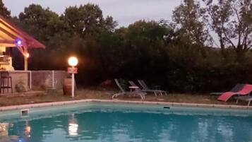 Una piscina con sillas de descanso y un edificio de techo rojo.