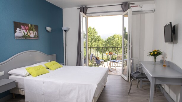Une chambre à coucher comprenant un lit, un bureau et un balcon avec une table et des chaises.