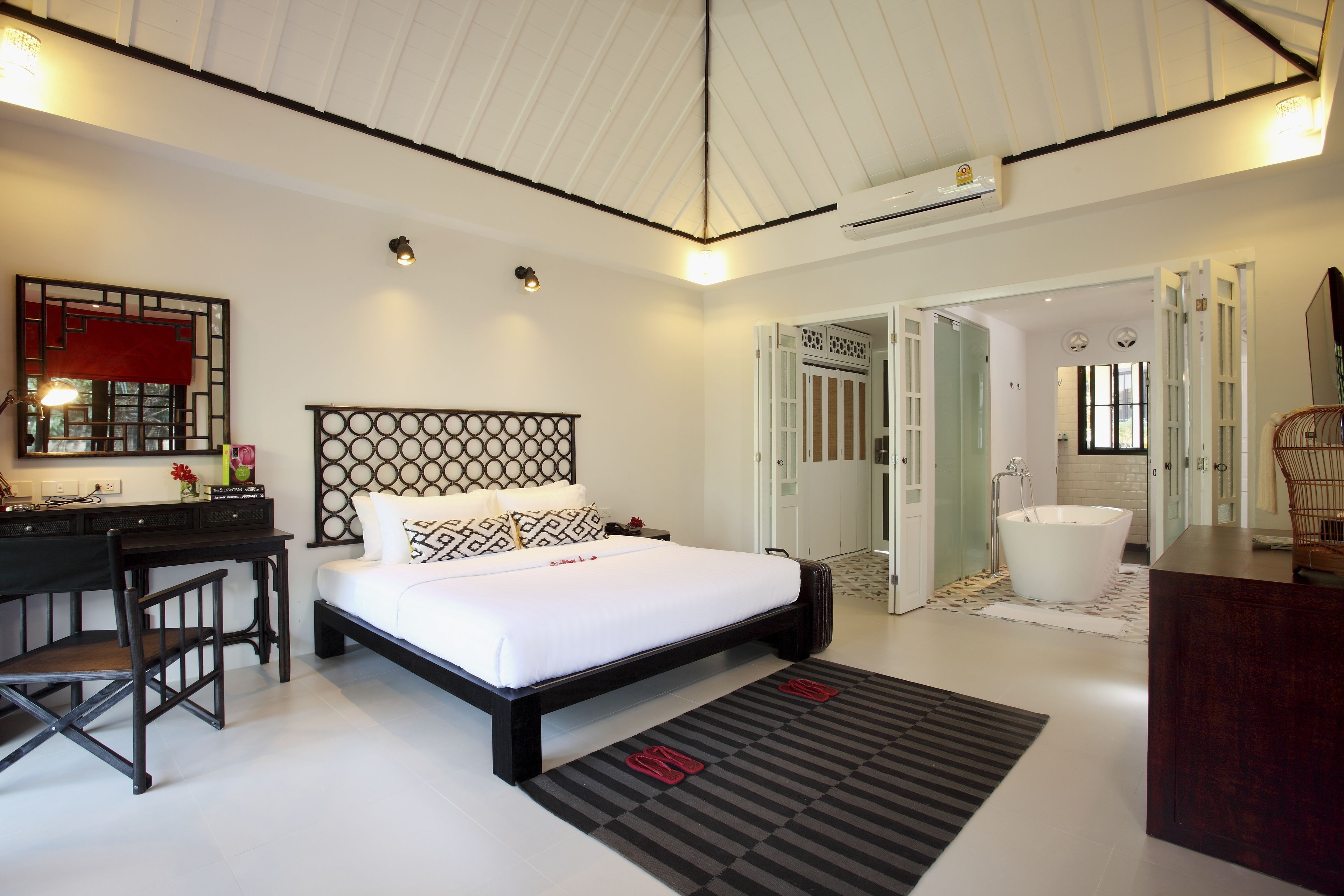 Een moderne hotelkamer met een groot bed, een bureau en een badkamer met een bad.