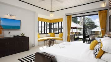 A modern bedroom with a large bed, a TV, a sofa by the window, and a balcony with yellow curtains.