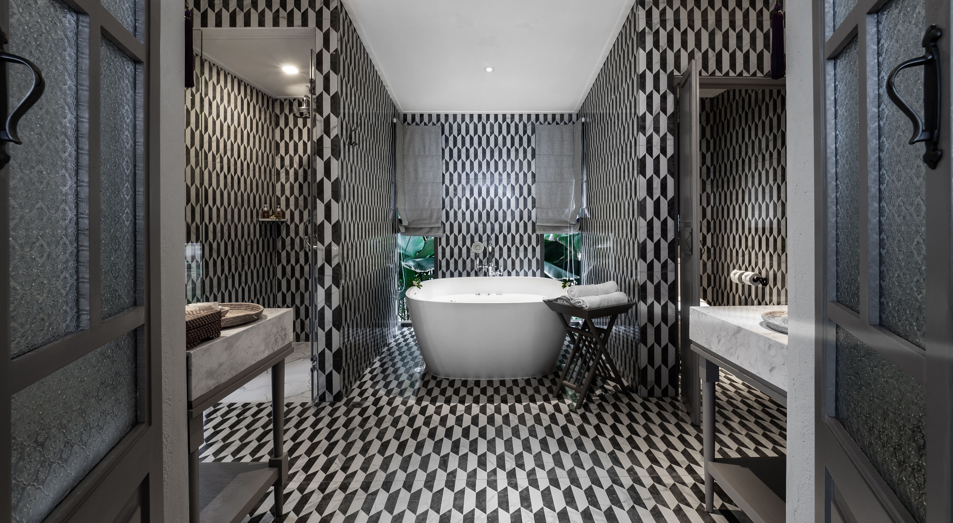 A modern bathroom with a freestanding bathtub, a vanity with a mirror, and a patterned floor.
