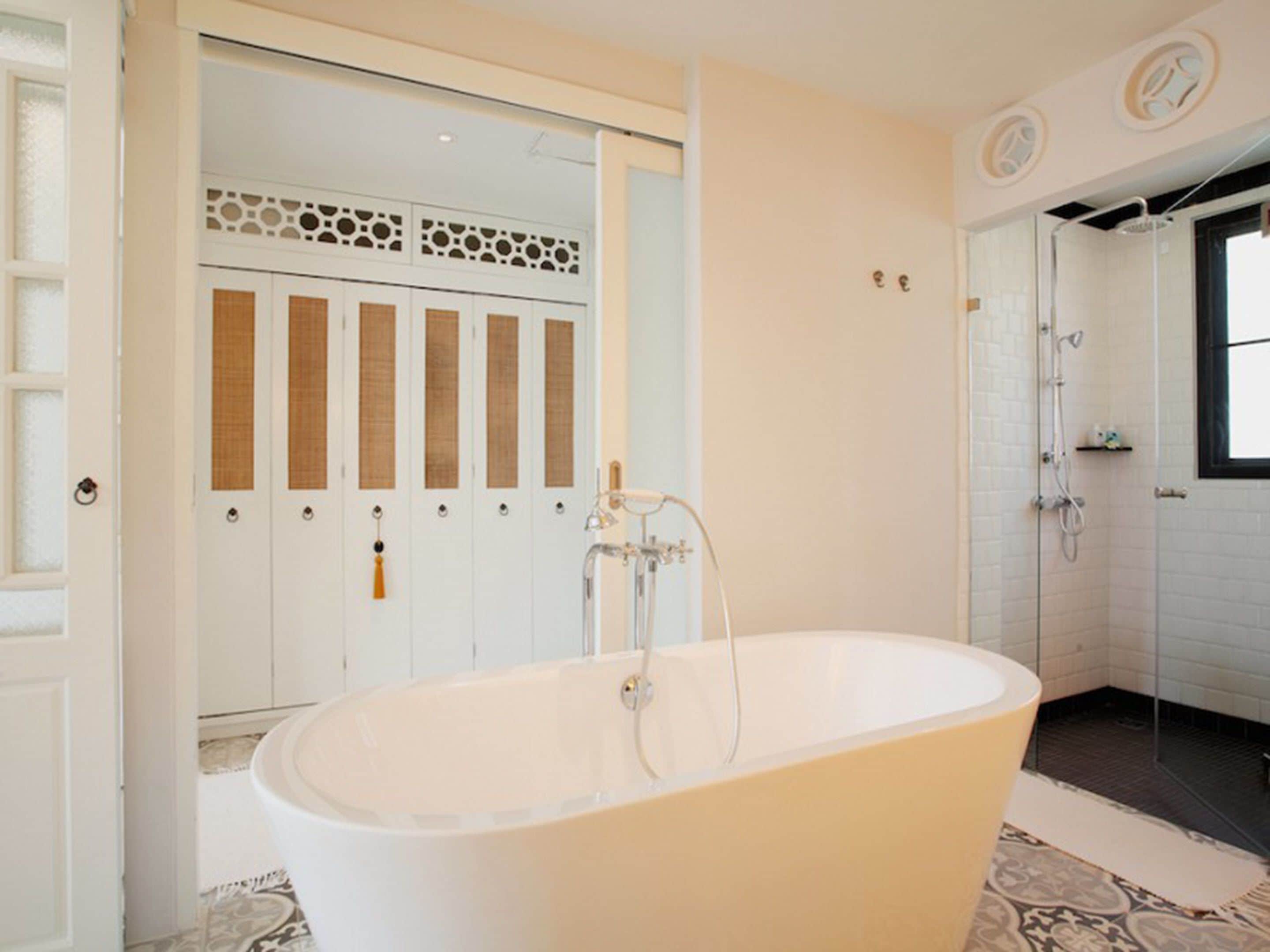 A modern bathroom with a freestanding bathtub, a shower area, and a set of doors with decorative panels.