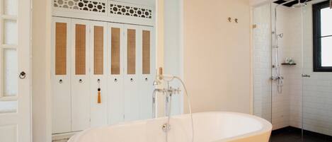 A modern bathroom with a freestanding bathtub, a shower area, and a set of doors with decorative panels.