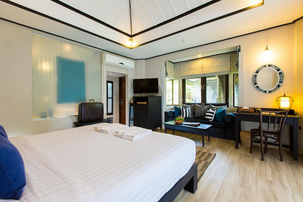 Une chambre d’hôtel dotée d’un grand lit, d’un bureau avec un ordinateur, d’une télévision et d’un coin salon offrant une vue sur l’extérieur.