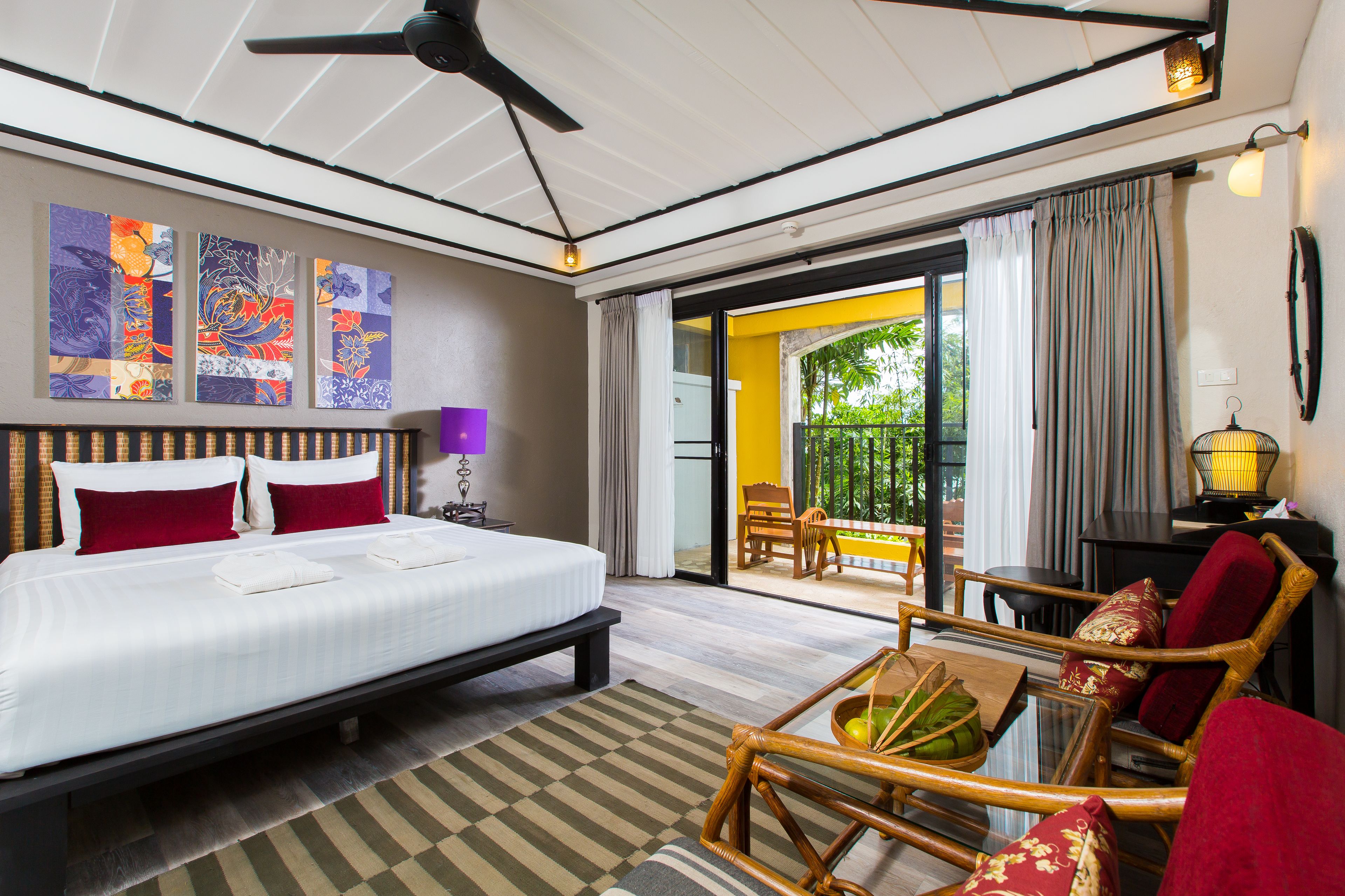 A hotel room with a bed, a dining area with a table and chairs, and a view of the outside.