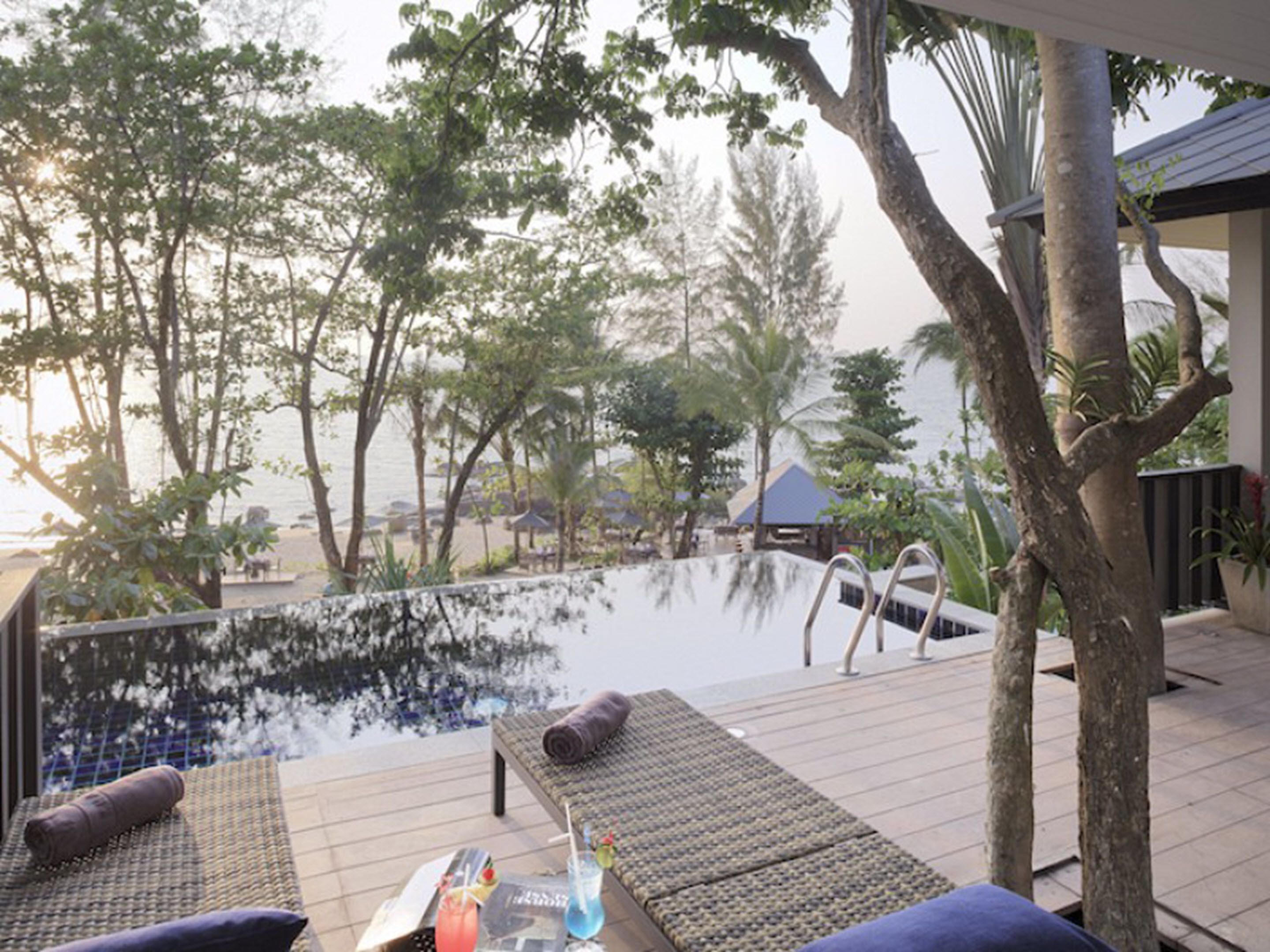 A poolside area with lounge chairs, a pool, and surrounding trees.