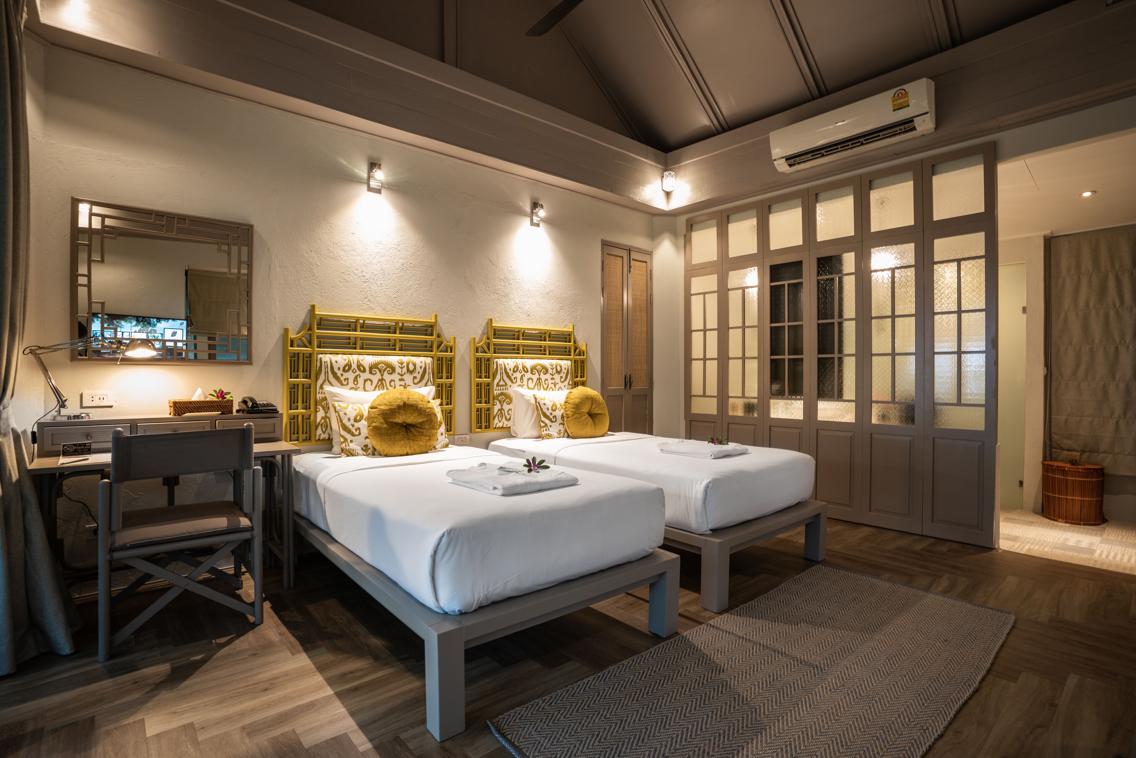 A hotel room with two beds, a desk, a chair, and a large window with a view.