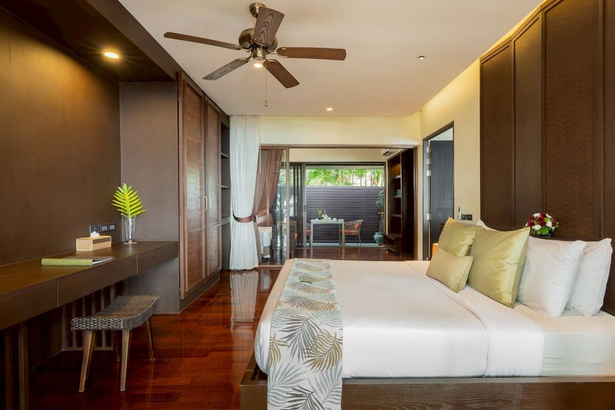 Un dormitorio moderno con una cama grande, un escritorio y un ventilador de techo.