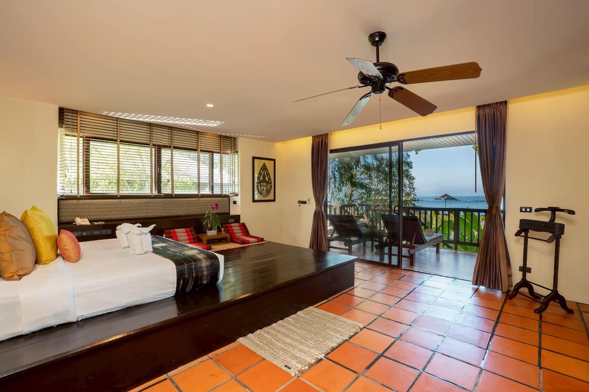 Un dormitorio moderno con una cama grande, ventilador de techo y balcón con vistas.