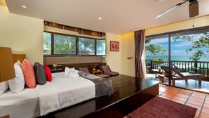 Una habitación de hotel moderna con una cama grande, un balcón con vistas al mar y un ventilador de techo.