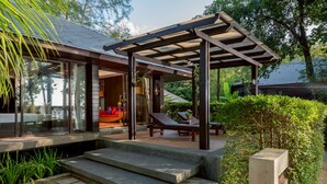 Un patio moderno al aire libre con una pérgola, un área de estar con un sofá rojo y una silla de lounge.