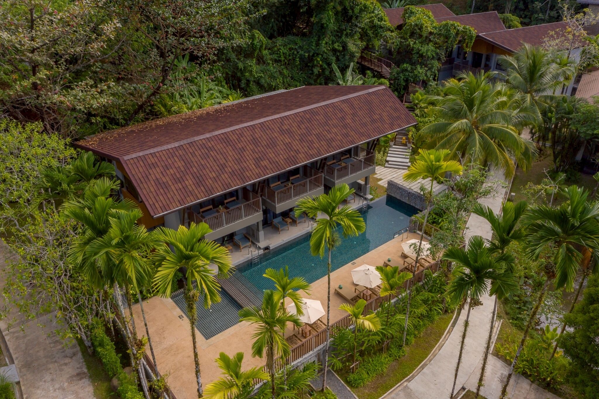Un complexe hôtelier doté d’une grande piscine, de nombreuses chambres et d’un environnement tropical luxuriant.