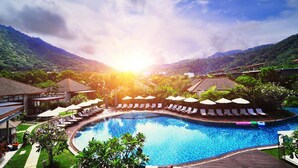 A resort pool with lounge chairs and umbrellas, surrounded by lush greenery and mountains. - Metadee Concept Hotel (Karon)