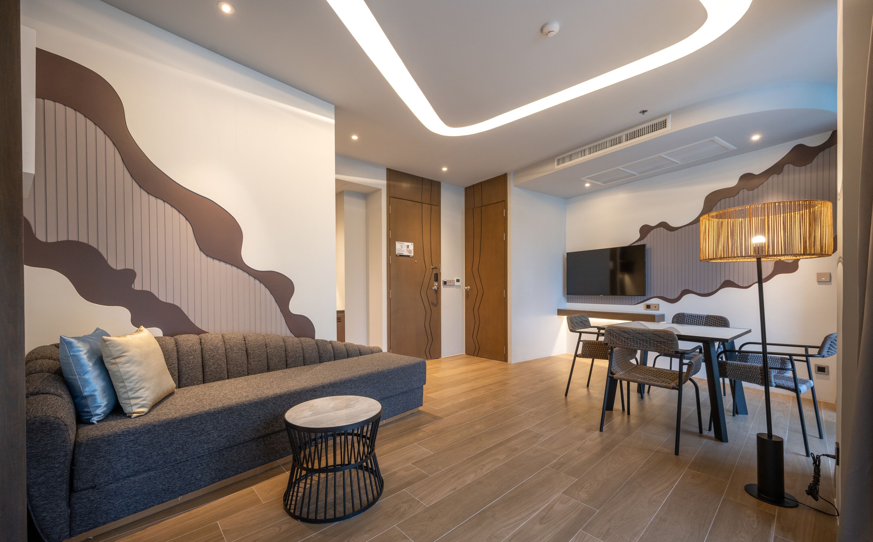 A modern living room with a sofa, a round coffee table, and a dining area with chairs and a table.