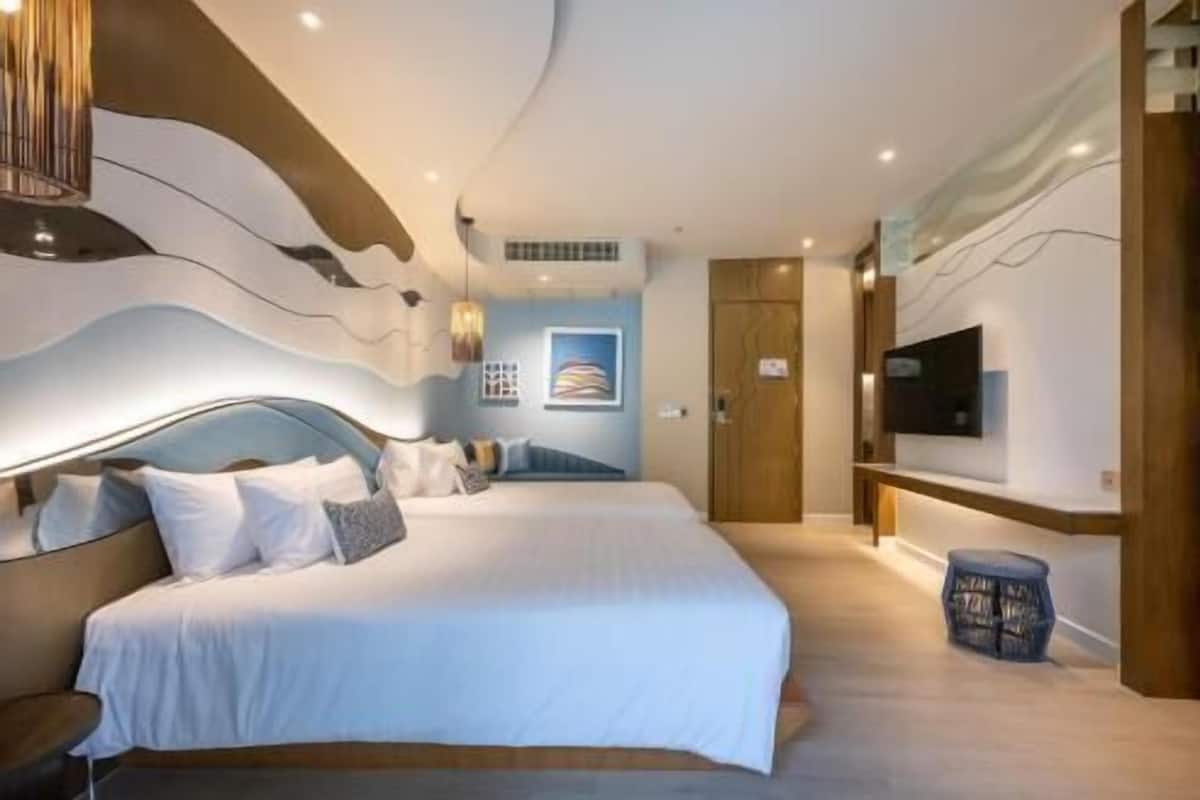 A modern hotel room with a large bed, a TV mounted on the wall, and a wooden door.