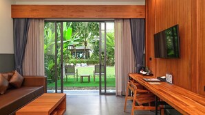 Una habitación moderna con un escritorio de madera, un sofá y un televisor montado en la pared.
