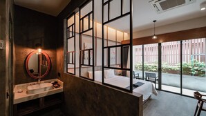 Habitación de hotel moderna con un ventanal grande, un lavamanos, una cama y vista al balcón exterior.