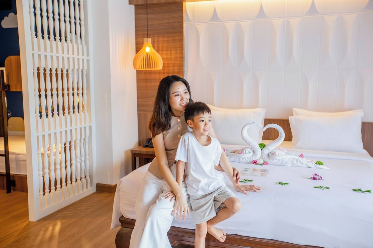Quarto com cama, mesa de cabeceira, painel decorativo na parede e luminária suspensa.