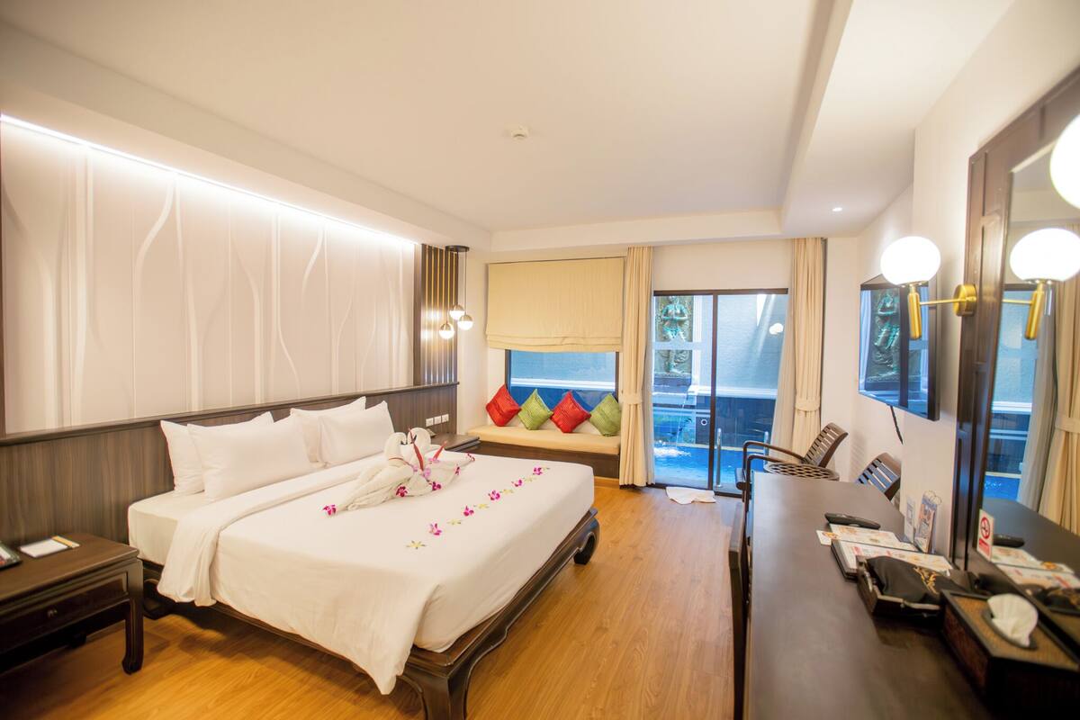 Quarto de hotel com uma cama grande, uma escrivaninha, uma cadeira, janela com vista e varanda.