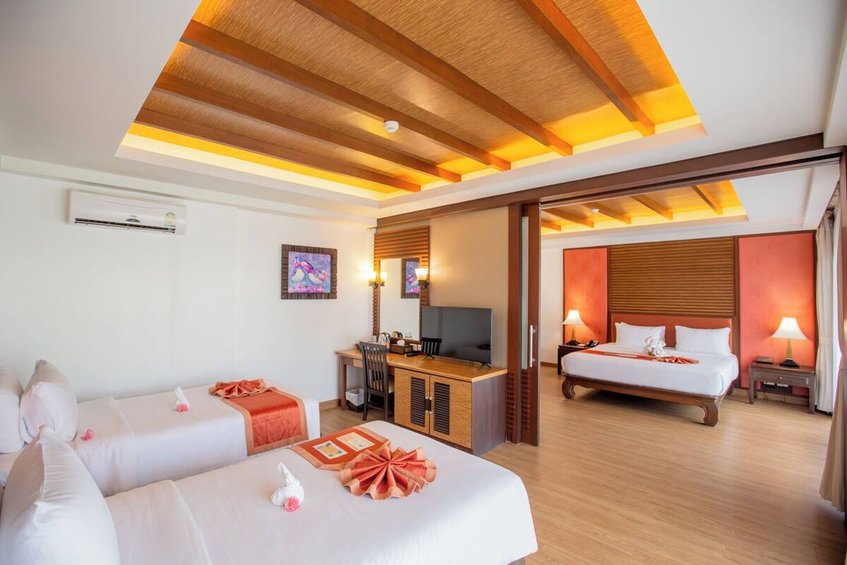 Quarto de hotel com duas camas, uma escrivaninha, televisão e banheiro.
