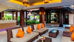 A spacious lobby with multiple seating areas, a reception desk, and large windows overlooking greenery. - Nipa Resort (Patong)
