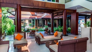 A spacious lobby with a high ceiling, wooden columns, and a seating area with sofas and chairs. - Nipa Resort (Patong)